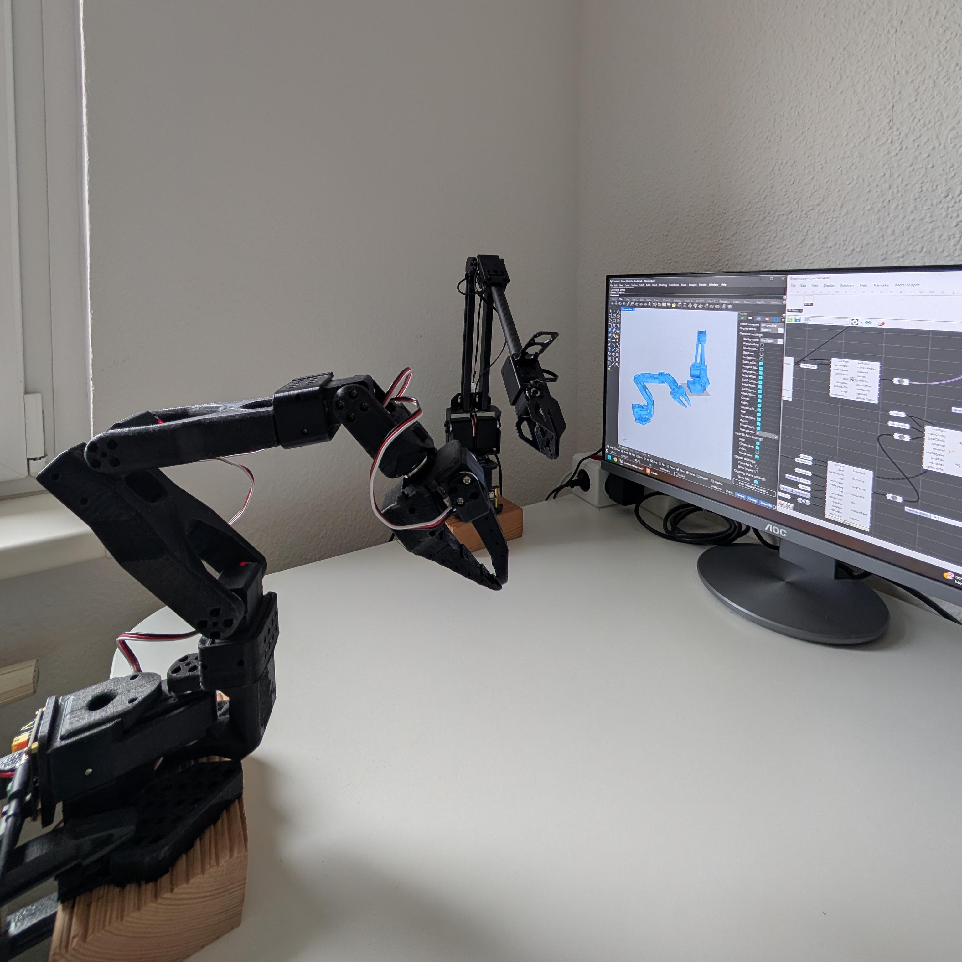 A 3D-printed robot arm wired up on a desk, with Rhino and Grasshopper open beside it showing the same arm as a URDF model